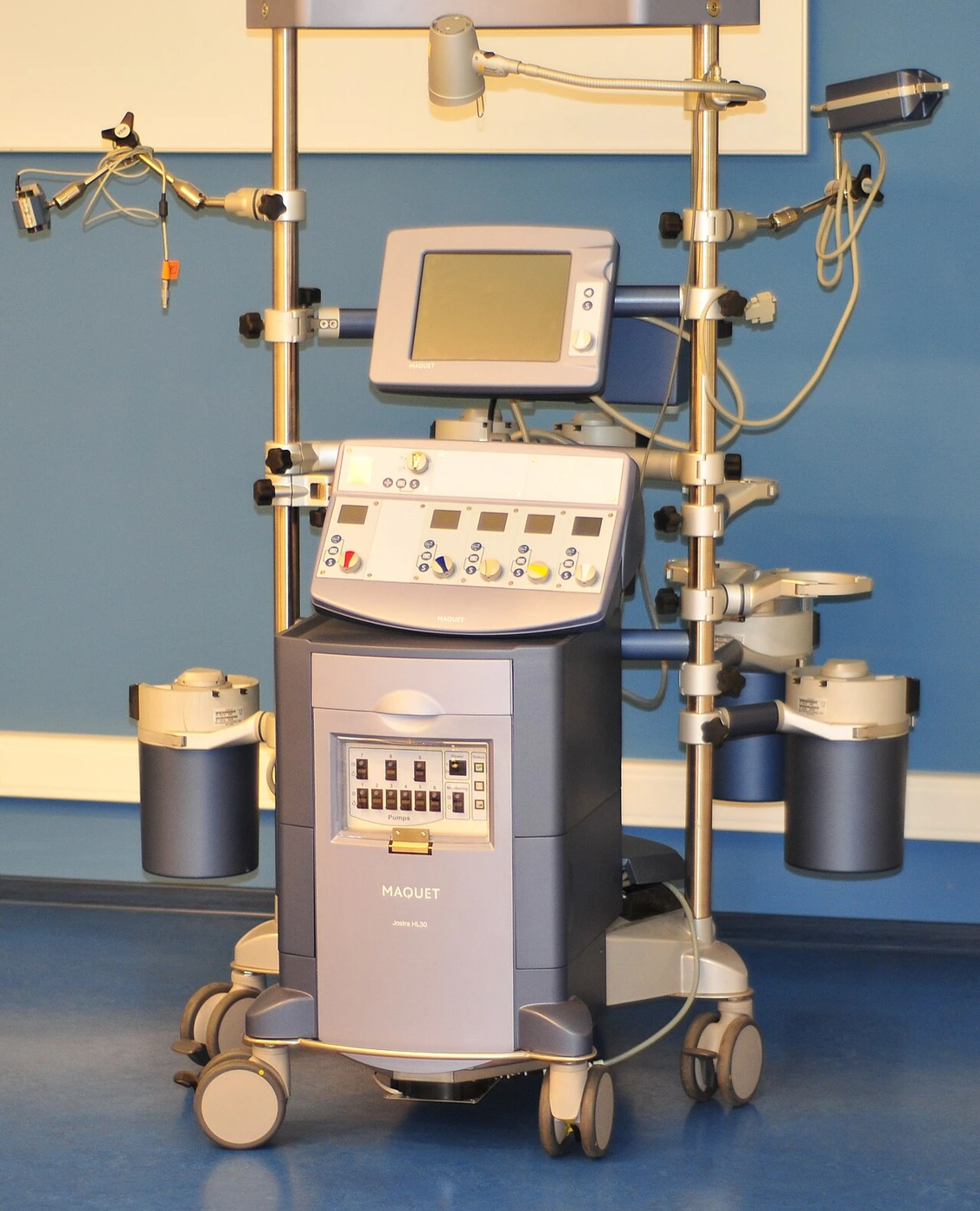 A tall wheeled console has a display, multiple pump controls and brackets for tubing and circuit components.