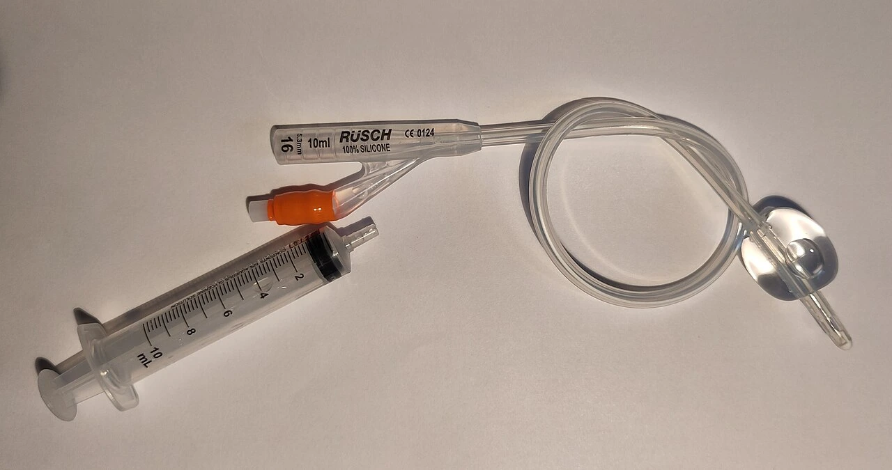 A flexible transparent tube with a large side balloon, separate proximal openings and a syringe beside it.