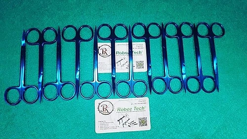 Several small metal scissors with round finger rings and short narrow blades lie on green cloth.