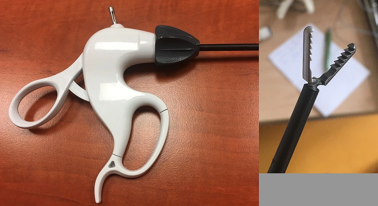 A long ring-handled instrument beside an enlarged view of two open serrated gripping jaws.