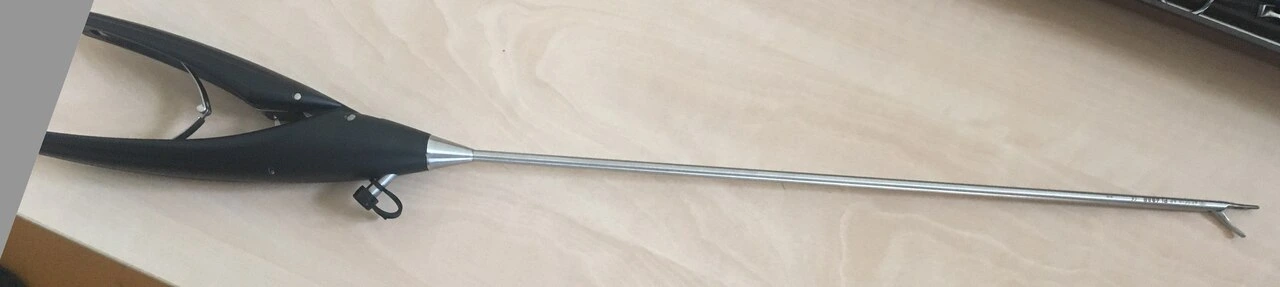 A slender long metal shaft ends in short jaws and has a dark locking handle with a finger loop.