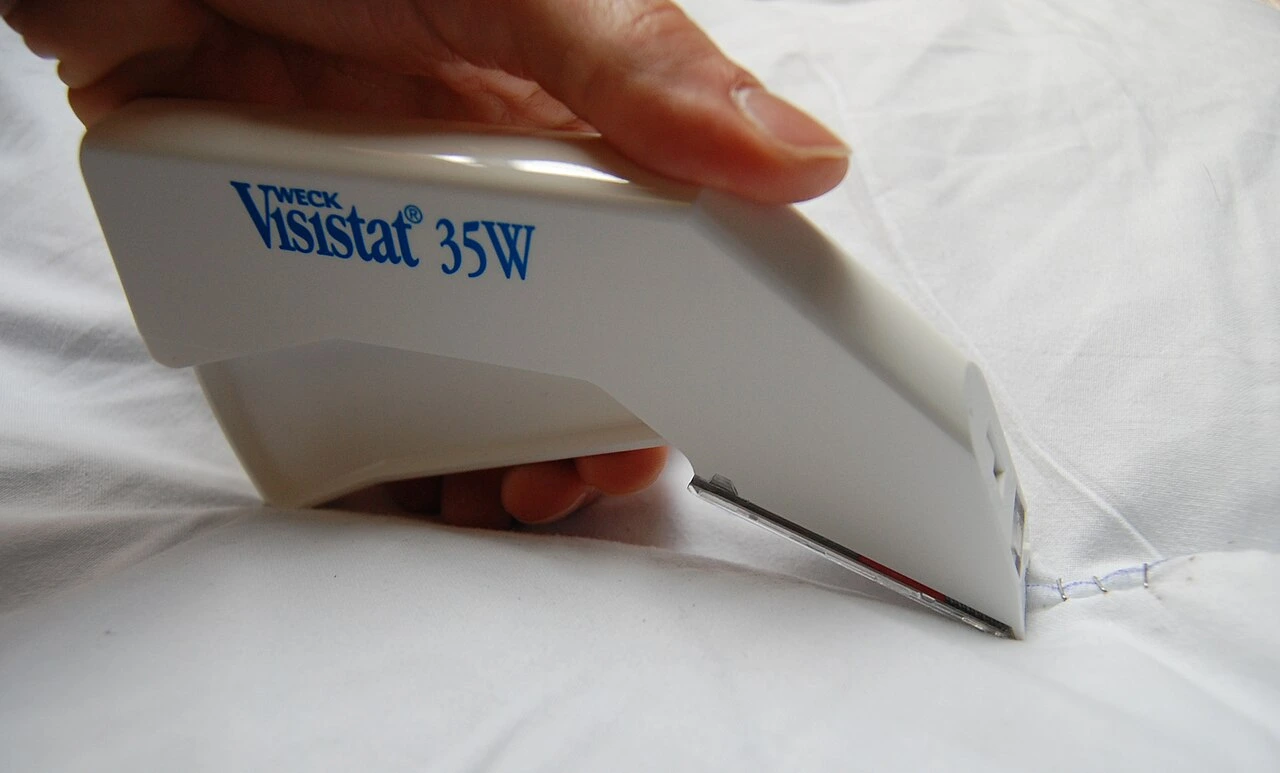 A handheld pale device has a squeeze trigger and a narrow metal tip at the skin-facing end.